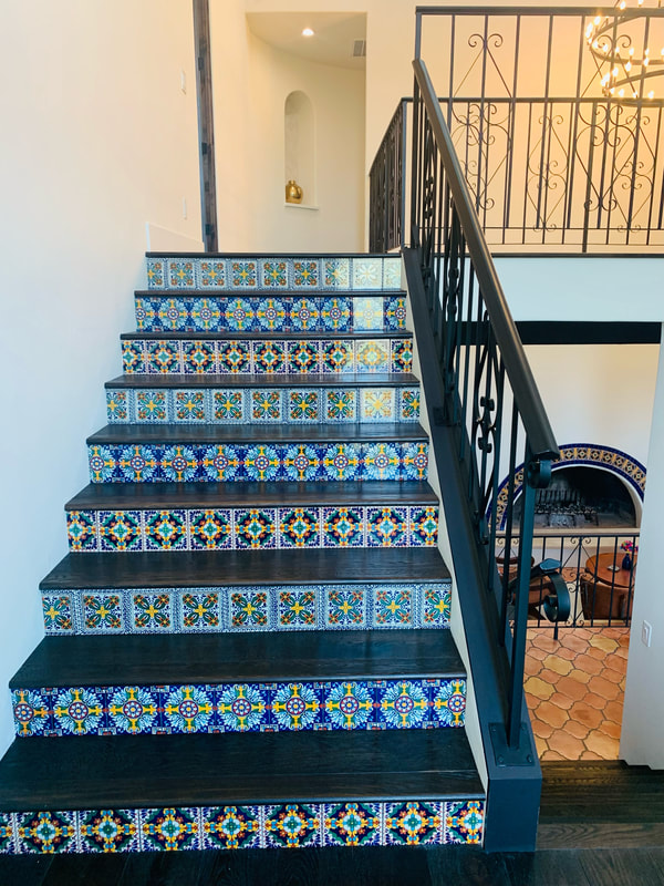 Spanish Revival design with Spanish style accent tile with dark hardwood stairs and black wrought iron railing 