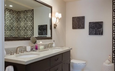 panish Revival design with dark walnut vanity and natural stone tile floor and black and white Spanish style tile