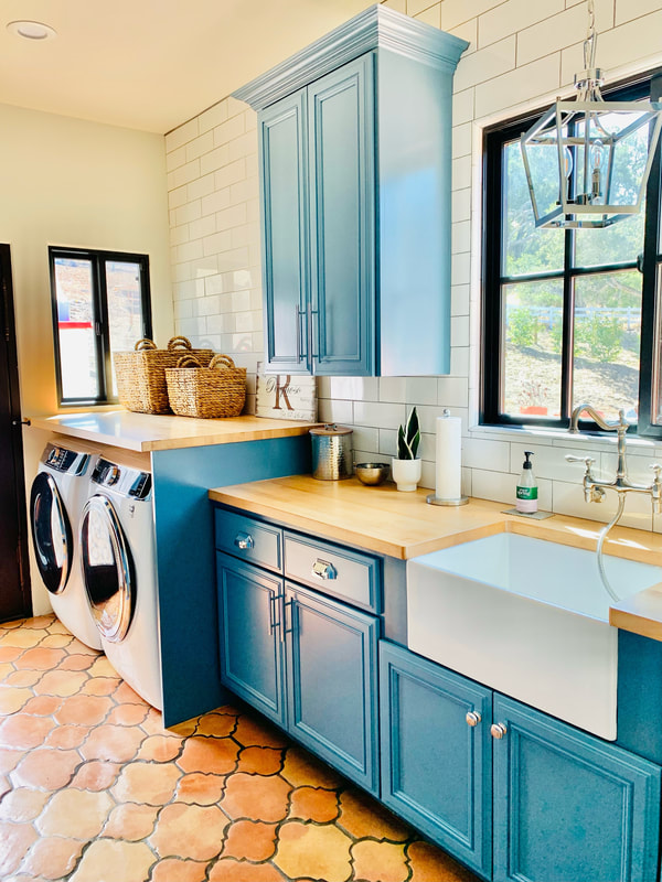 Spanish Revival design laundry room with custom cabinets in a teal color with natural butcher block countertops 