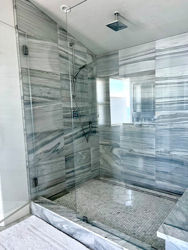 Modern Coastal design shower with gray natural stone tile with heavy glass shower door in Master bathroom 