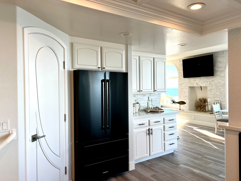 Modern Coastal design with black appliances and natural stone backsplash in kitchen 
